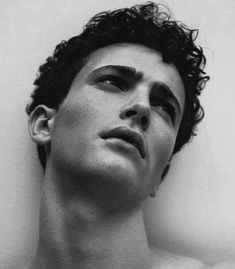 black and white photograph of a young man with curly hair looking up at the sky