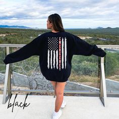 a woman wearing an american flag sweater standing on a balcony