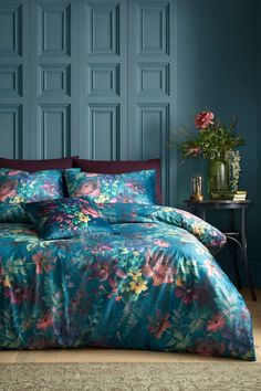 a bedroom with blue walls and flowers on the bedspread, along with a plant