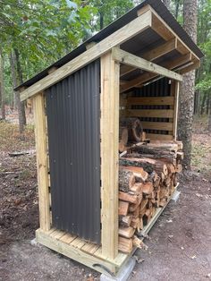 there is a shed made out of wood in the woods with logs stacked around it