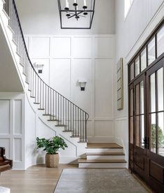 an entryway with stairs, potted plant and chandelier