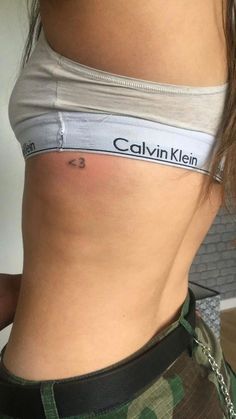 the back of a woman's stomach with her name tattooed on it, while she is wearing camo shorts