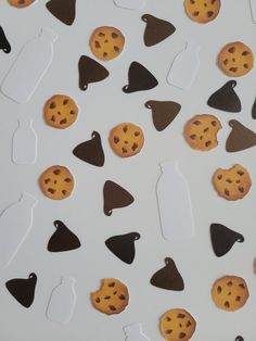 chocolate chip cookies and milk bottles are arranged on a white surface with cutouts in the shape of shapes