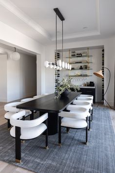 a dining room table with white chairs and lights hanging from it's centerpiece