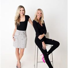 two women sitting on stools posing for the camera