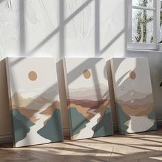 three abstract paintings on canvases in front of a window with sunlight streaming through them