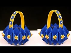 two blue baskets with yellow handles and flowers on them, one is folded to look like an origami flower