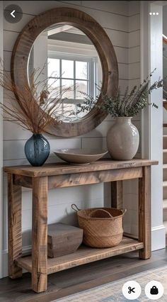 a wooden table with a mirror on top of it next to a basket and vase