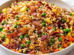 a white bowl filled with rice, peas and bacon on top of a table cloth