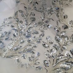 silver sequins and feathers on white fabric