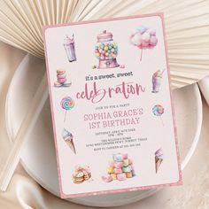 a pink birthday card with sweets and candies on it, next to a fan