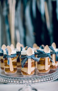 small desserts in glass jars with wooden spoons on a silver platter at a wedding reception