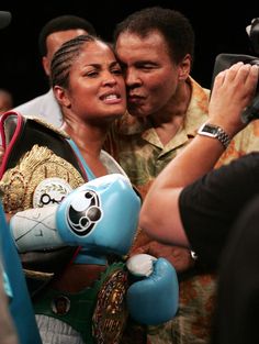 a woman holding a blue boxing glove is surrounded by photographers