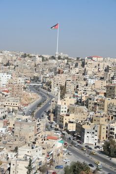 an aerial view of a city with lots of buildings and a flag flying high in the sky