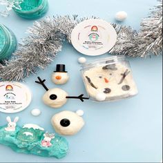 some snowmen and other decorations on a blue table with tinsels, candy