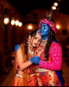 two women dressed in colorful costumes hugging each other