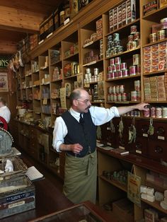 a man standing in front of a store filled with shelves full of food and spices