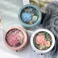 three small round boxes with flowers in them