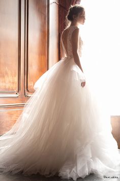 a woman standing in front of a window wearing a wedding dress with sheer back and sleeves