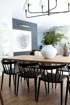 a dining room table with black chairs and a white vase sitting on top of it