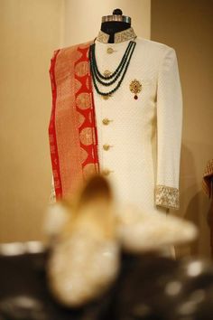 a mannequin wearing a white and red outfit with beads on it's neck