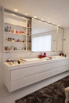 a white bathroom with two sinks and large mirror above the sink is lit by recessed lights