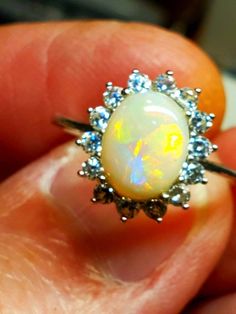 Real pretty 9x7mm white opal surrounded by a star pattern of sparkling cubic zirconia crystals. I just love this little stone. White Ethiopian Opal Ring For Promise, White Ethiopian Opal Ring For Anniversary, White Ethiopian Opal Ring For Wedding, White Ethiopian Opal Ring As Gift, White Ethiopian Opal Wedding Ring, White Ethiopian Opal Promise Ring, White Opal Cabochon Promise Ring, White Opal Ring With Halo Setting For Gift, White Opal Cabochon Ring For Promise