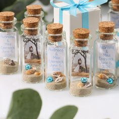 wedding favors in glass bottles with sand and sea shells on the bottom, tied with a blue ribbon