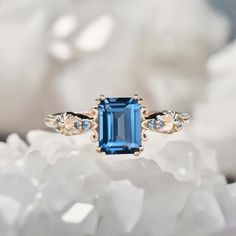 a blue stone ring sitting on top of white flowers