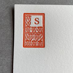 the letter s is made out of red and white paper with an orange stamp on it