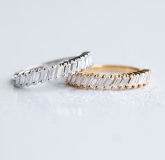 two gold and silver rings with baguettes on white background, side by side