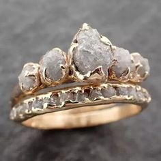 two gold wedding rings with rough white diamonds on each one, set against a black background