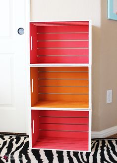 a red and orange bookcase sitting on top of a zebra print rug next to a white door