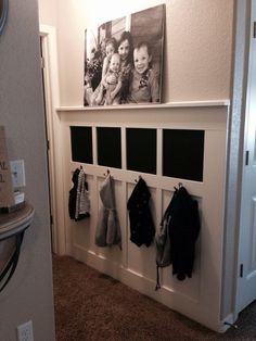 a coat rack with pictures and coats hanging on it's sides in a hallway