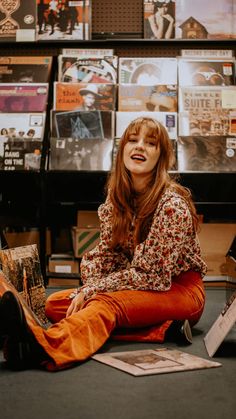 a woman sitting on the floor with her legs crossed in front of bookshelves