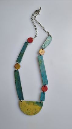 a necklace that has been made with different colored beads and metal chains on it,