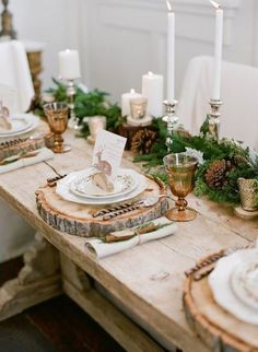 a wooden table topped with white plates and candles