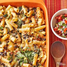 a casserole dish filled with pasta and vegetables next to a bowl of salsa