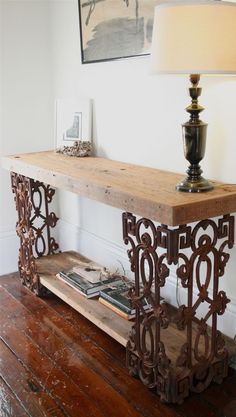 a wooden table sitting on top of a hard wood floor next to a lamp and painting