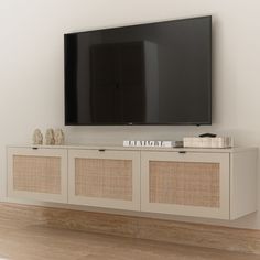 a flat screen tv mounted to the side of a white entertainment center with wicker doors