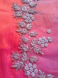 an embroidered fabric with silver flowers and leaves on pink silk, showing the beading