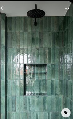 a green tiled bathroom with a shower head