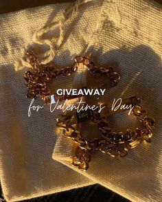 a pair of gold chains sitting on top of a white cloth with the words giveaway for valentine's day