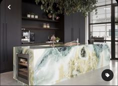 a marble counter top in a kitchen with black cabinets and plants hanging from the ceiling