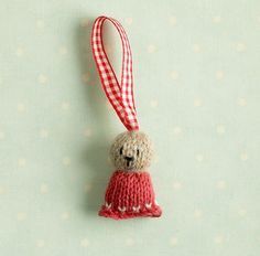 a red and white knitted ornament hanging from a string on a wall