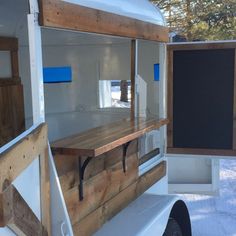 the back end of a white trailer with wood accents