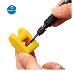 a hand holding a yellow plastic object with a screwdriver in it's middle