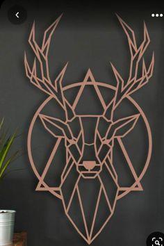 a deer head made out of geometric shapes on a wall next to a potted plant