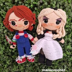 two crocheted dolls sitting next to each other on top of green plants and grass