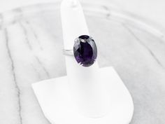 This exceptional amethyst commands attention! Generous in size, this gemstone sparkles with juicy hues of violet, fuchsia, and royal purple. A simple setting of 18 karat white gold lets the amethyst be the star of the show. Metal: 18K White Gold Gem: Amethyst 12.20 Carats Gem Measurements: 12.9 x 16.9 mm, Oval Ring Size: 6.25 Marks: "750" Stamped on the inside band Faceted Purple Amethyst Ring For Formal Occasions, Formal Faceted Purple Amethyst Ring, Formal Sterling Silver Purple Amethyst Ring, Formal Purple Amethyst Ring In Sterling Silver, Formal Purple Tanzanite Jewelry, Elegant Faceted Amethyst Ring In Sterling Silver, Elegant Purple Platinum Jewelry, Elegant Purple Diamond Cut Amethyst Ring, Purple Platinum Jewelry For Anniversary